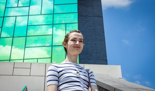 В 17 лет Ханна Каиро разгадала важную математическую загадку. 5 Женщина стоит на фоне отражающего здание.