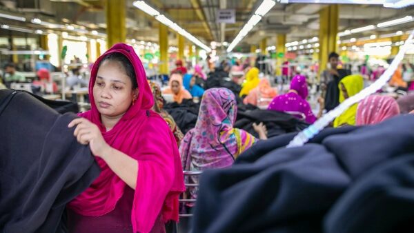 Работники швейной фабрики в яркой одежде концентрируются на производстве одежды.