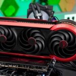 Красная видеокарта с тремя вентиляторами на фоне компьютера, детали геймерских компонентов.