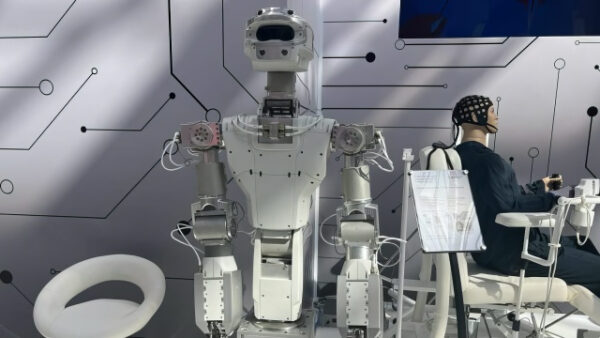 Робот рядом с человеком в шлеме на выставке технологий.