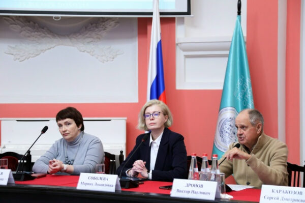 Конференция с участниками за столом в зале с флагами России и организации.