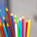 Цветные карандаши в стакане на размытом фоне.