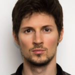 Изображение человека с темными волосами и бородой на светлом фоне.