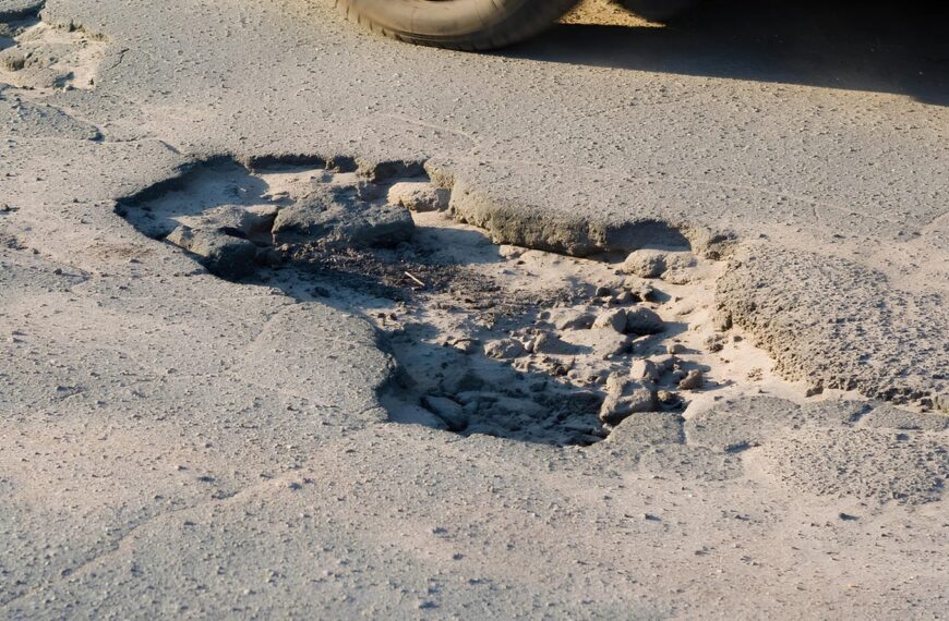 Яма на асфальте, крупный план дорожного покрытия с выбоиной.