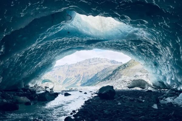 Вид из ледяной пещеры на горы и реку, природный ландшафт.