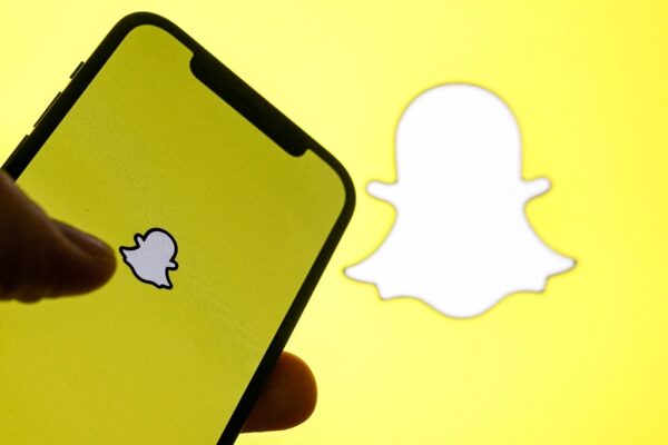 Смартфон с логотипом Snapchat на жёлтом фоне крупным планом.