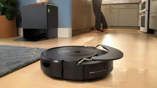 Робот-пылесос Roomba в кухне, убирает мусор с пола возле коврика и станции.