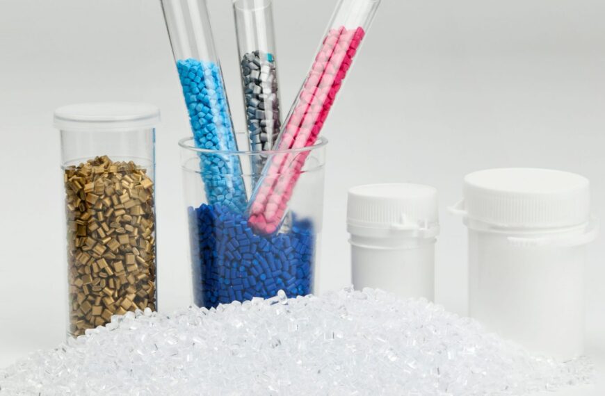 Пластиковые гранулы разных цветов в пробирках и контейнерах на белом фоне.