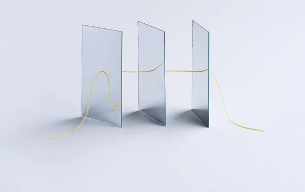 Нить проходит сквозь три стеклянные панели на сером фоне.