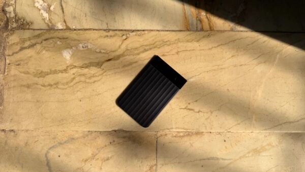 Чёрный внешний жёсткий диск на светлом мраморном полу с тенями.