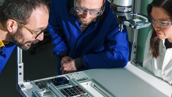 Люди в синих халатах работают с научным оборудованием в лаборатории.