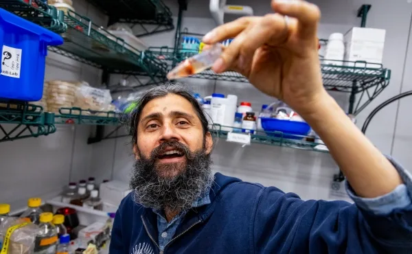 Ману Пракаш держит в руках небольшую трубочку с красным пятном внутри.