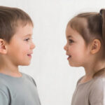 Дети стоят лицом друг к другу в нейтральной одежде на светлом фоне.