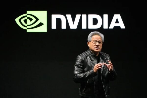 Мужчина на фоне логотипа NVIDIA в черной кожаной куртке, делает презентацию.