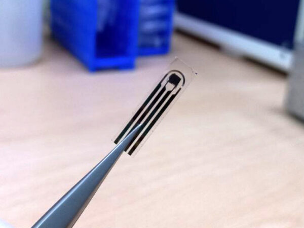 Прозрачный микрочип в пинцете на лабораторном столе, технология, микроэлектроника.