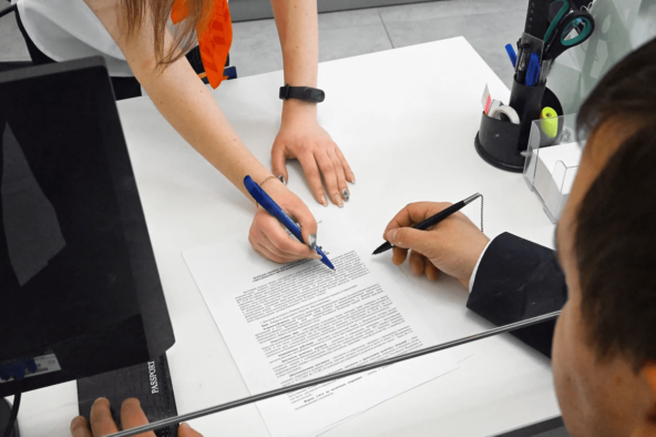 Два человека подписывают деловой документ в офисе.