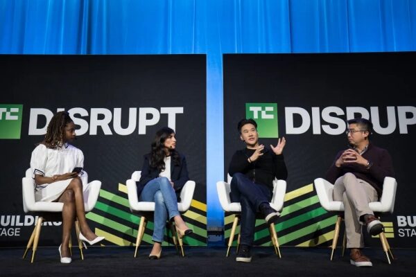 Панельная дискуссия на конференции TechCrunch Disrupt на фоне логотипов.