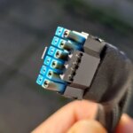 Кабель питания EPS зажат в руке, показан крупным планом на фоне улицы.