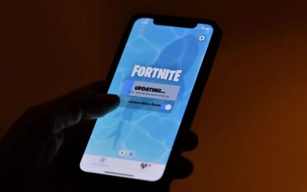 Человек держит смартфон с обновлением Fortnite на экране.