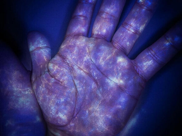Рука под ультрафиолетом, светящиеся узоры на ладони.