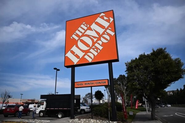 Вывеска Home Depot на парковке магазина на фоне голубого неба.