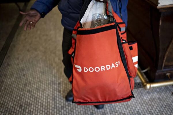 Доставка DoorDash, курьер с красной сумкой в помещении.