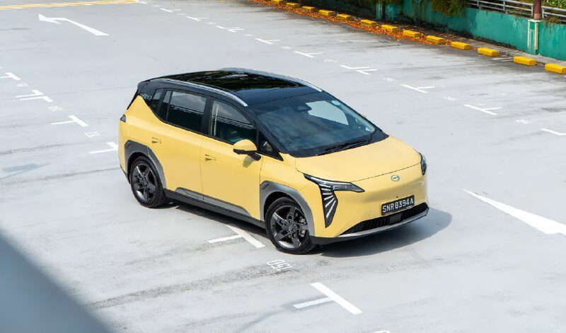 Жёлтый современный автомобиль на парковке в городской среде.