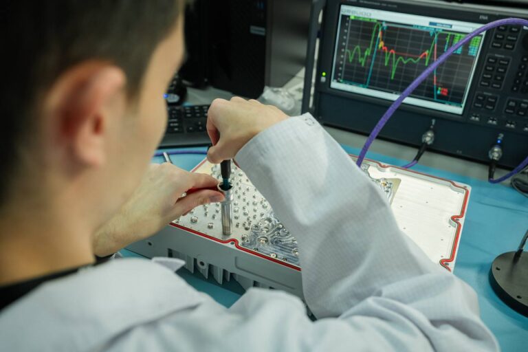 Инженер работает с электрическим оборудованием в лаборатории, на экране графики.