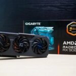 Видеокарта Gigabyte AMD Radeon RX 9060 XT с коробкой на фоне, три вентилятора.