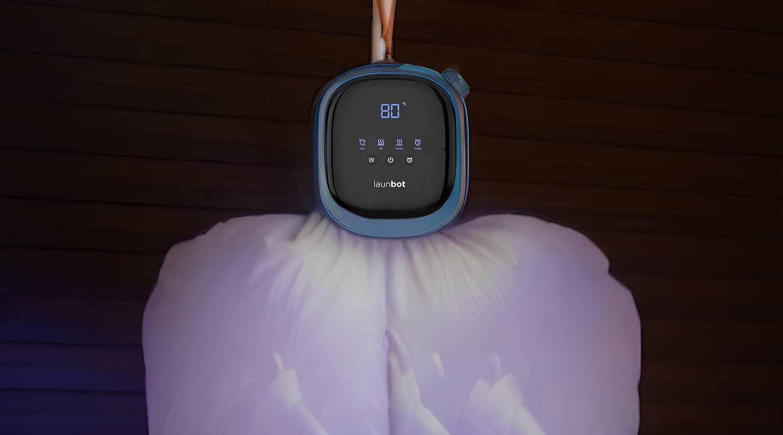 Компактный электрический прибор с дисплеем для ухода за одеждой, установленный на подушке.