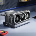 Внешняя видеокарта на столе с ноутбуком и игровой консолью.