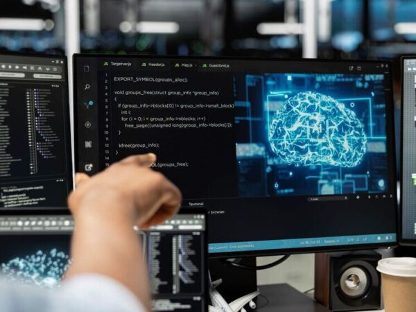 Человек работает с кодом на компьютере, на экране мозг с цифровой графикой.