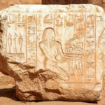 Древнеегипетская каменная плита с иероглифами и изображением фигуры в профиль.