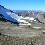 Горный ландшафт с ледником и скалами на фоне голубого неба.