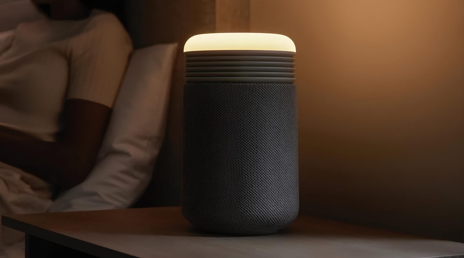 Умная колонка с подсветкой на прикроватном столике в темной комнате.