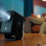 Компактный проектор на столе в уютной комнате с мягким освещением.