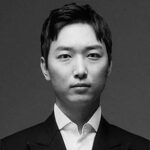 Человек в классическом костюме на сером фоне, стильный деловой образ.