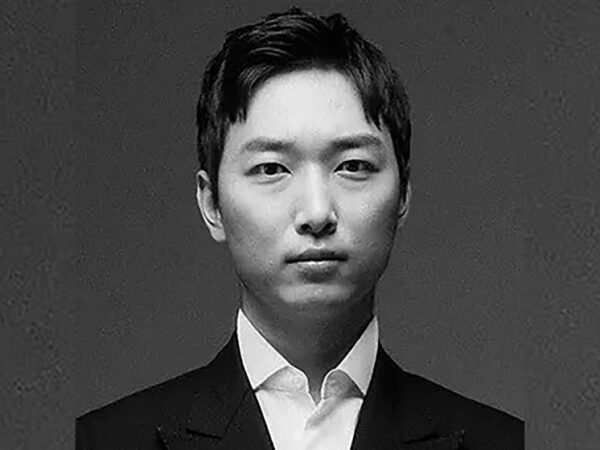 Человек в классическом костюме на сером фоне, стильный деловой образ.