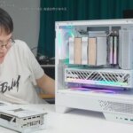 Компьютер в белом корпусе с RGB-подсветкой и разобранной видеокартой на столе.