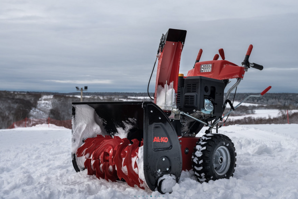 Снегоуборочная машина на заснеженной дороге зимой для очистки территории от снега.