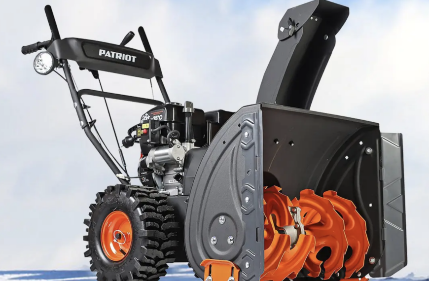 Снегоуборочная машина на зимнем фоне, готовая к работе на снегу.