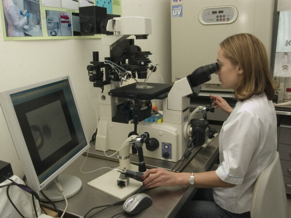 Женщина работает с микроскопом в исследовательской лаборатории.