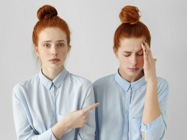 Две девушки с рыжими волосами в голубых рубашках, одна показывает на другую пальцем.