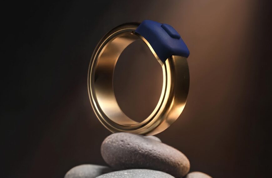 Золотое кольцо с синим элементом на фоне темной композиции из камней.