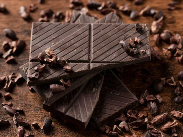 Кусочки темного шоколада и какао-бобы на деревянной поверхности.
