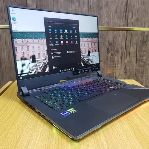 Игровой ноутбук на столе с включённым экраном и подсветкой клавиатуры.