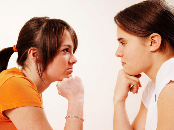 Две женщины смотрят друг на друга, сидя лицом к лицу, задумчивый вид.