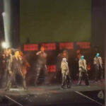 Концертное выступление с хореографией на сцене при ярком освещении.