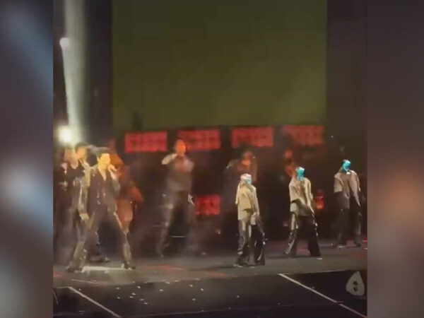 Концертное выступление с хореографией на сцене при ярком освещении.