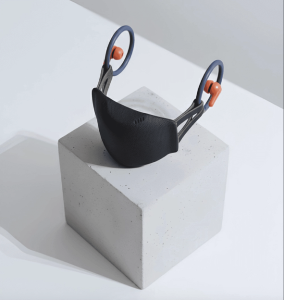 Японский стартап Verne Technologies представил на CES концепт маски с шумоподавлением для разговоров в публичных местах 1 Современная черная маска на сером кубе, стильный дизайн.